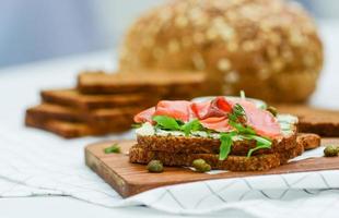Smoked salmon sandwich with cheese, pistachio and salad leaves, brown breads photo