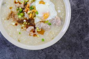 congee, gachas de arroz con cerdo picado, huevo cocido, ideal para el desayuno. foto