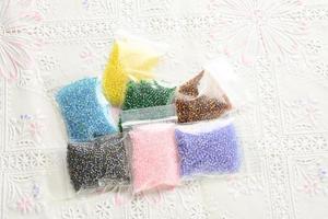 Colorful beads on white fabric surface. Various of shapes and colors to make jewelry photo