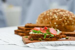 Sándwich de salmón ahumado con queso, pistacho y hojas de ensalada, pan integral foto