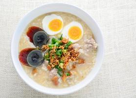 congee, gachas de arroz con carne de cerdo picada, huevo cocido y huevo del siglo, ideal para el desayuno. foto