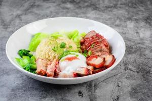 cerdo rojo asado y cerdo crujiente en salsa roja, servido con arroz y vegetales en un plato blanco. foto