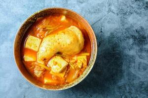 Korean traditional Kimchi soup with chicken and soft tofu photo