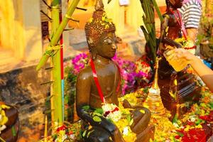 Watering Buddha statues with scented water and flower petals on Lao New Year photo