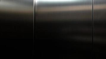 hoja grande de acero inoxidable con luz golpeando la superficie para el fondo, dentro del ascensor de pasajeros, reflejo de la luz en una textura de metal brillante, fondo de acero inoxidable. foto
