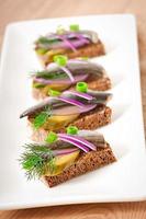 Sandwiches of rye bread with herring, onions and herbs. photo
