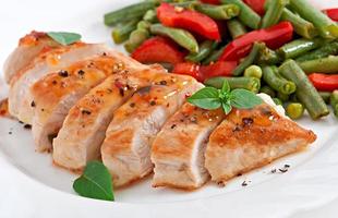 Chicken breast with vegetables and sauce decorated with basil leaves photo