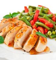 Chicken breast with vegetables and sauce decorated with basil leaves photo