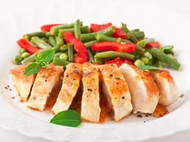 Chicken breast with vegetables and sauce decorated with basil leaves photo