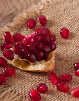 pomegranate seeds on a background of wood and burlap
