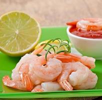 tails of shrimps with fresh lemon and rosemary in plate on wooden old background photo