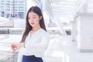 una joven mujer asiática de negocios va a la oficina o al lugar de trabajo que mira en la gran ciudad con edificios comerciales como fondo. foto