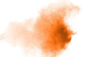 Abstract orange powder explosion on white background. Freeze motion of orange dust particles splash. photo