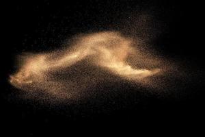 Brown colored sand splash against dark background. Dry river sand explosion isolated on black background. Abstract sand cloud. photo