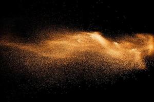 explosión de partículas de polvo naranja sobre fondo negro. salpicaduras de polvo de polvo de color. foto