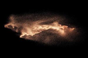 Abstract sand cloud.Brown sand splash against dark background. Brown dust explosion. photo