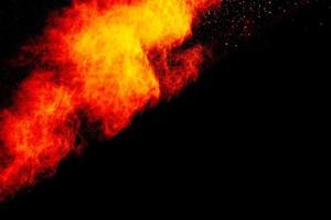 Red orange color powder explosion cloud isolated on black background. photo