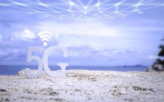 símbolo de 5g blanco con wifi y red de transmisión en la playa de piedra con cielo azul. red internet, comunicación inalámbrica y estándar 5g de concepto social de señal. foto