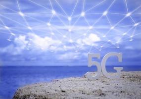 símbolo de 5g blanco con wifi y red de transmisión en la playa de piedra con cielo azul. red internet, comunicación inalámbrica y estándar 5g de concepto social de señal. foto