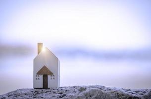 The miniature white house on stone with background of sea beach. Family lifestyle and building or rent concept. photo