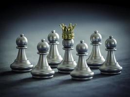 la corona de oro del peón de ajedrez plateado está rodeada de piezas de ajedrez plateadas para luchar con el trabajo en equipo hacia la victoria, el concepto de estrategia empresarial y el concepto de líder y trabajo en equipo para el éxito. foto