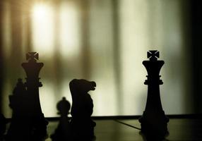 Silhouette of chess pieces on white background. Silhouette of black king are leader to fight with teamwork to victory. Leader,strategy and checkmate concept for success. photo