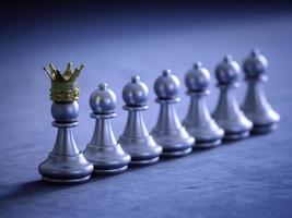 Silver chess pawn wear gold crown to leadership on chess board with network and communication to fighting with teamwork to victory, business strategy concept for success. photo