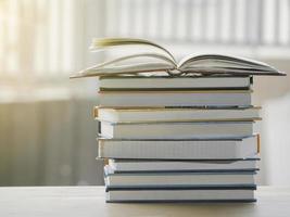 A simple composition of many books, stack or pile of books on wooden table, one of them open with copy space. photo