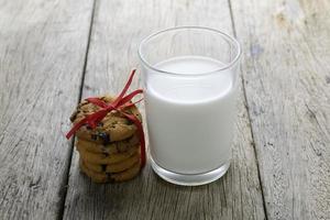 galletas y un vaso con leche en la mesa de madera foto