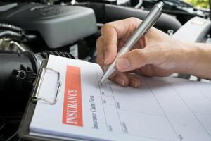 Mechanic Inspecting damage car and filling in accident report form photo