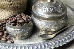 Silver cup and Coffee beans in sackcloth bag on wooden background photo