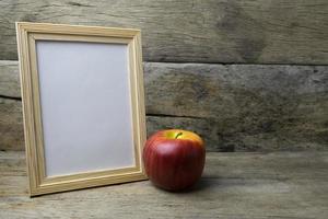 marco de fotos de madera y manzana roja sobre mesa de madera