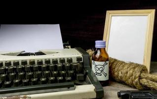 máquina de escribir con página de papel y veneno y pistola. concepto escritor romance suspenso foto