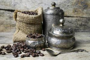 Silver cup and Coffee beans in sackcloth bag on wooden background photo