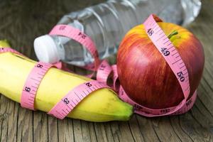 Healthy eating concept, tape measure, fruit and water bottle on a wooden background photo