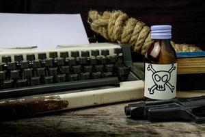 máquina de escribir con página de papel y veneno y pistola. concepto escritor romance suspenso foto