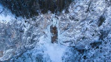 Aerial drone view of frozen waterfall with some water running through. Beautiful and magical winter holiday scenery for nature lovers. Scenery out of Narnia world. Unimaginable fairy tail sightseeing. photo