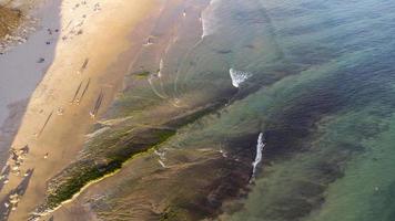 increíble vista aérea escénica de drones de la playa y el océano con olas tranquilas durante una puesta de sol con colores vibrantes. algarve, portugal. aguas claras vacaciones y vacaciones. antecedentes. playa con rocas. foto