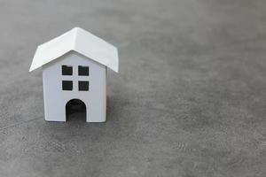 Simply design with miniature white toy model house on concrete stone grey background. Mortgage property insurance dream home concept. Copy space. photo