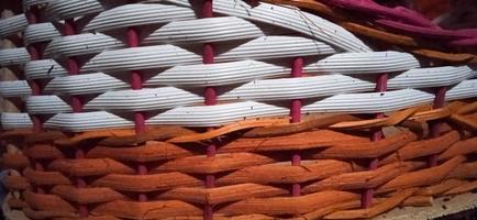 Criss-cross traditional bamboo basket pattern with orange, white, and pink color combinations. photo