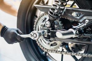 Mechanic using a wrench and socket to Remove and Replace Rear Motorcycle Wheel  , maintenance, repair motorcycle concept in garage .selective focus photo