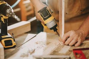 Carpenter use Cordless Drill ,Drive the screw on wooden plate.DIY maker and woodworking concept. selective focus photo