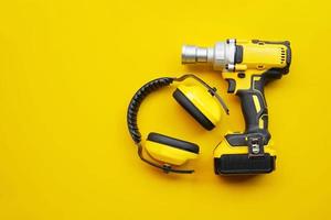 power tools,Ear Muffs, Mid-Range Cordless Impact Wrench on yellow background .Safety Equipment concept . photo
