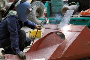 soldador que trabaja con una máquina de soldadura por arco en el sitio de construcción foto