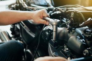 Mechanic using a wrench and socket on cylinder head of a motorcycle .maintenance,repair motorcycle concept in garage .selective focus photo