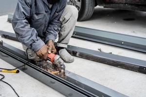 Worker using angle grinder machine cutting metal in factory photo