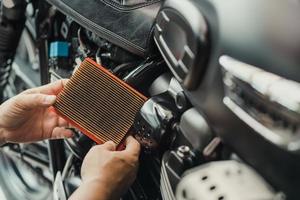 mechanic holding dirty Engine Air Filter over motorcycle, scooter  .mechanic working in garage. Repair and maintenance motorcycle concept photo