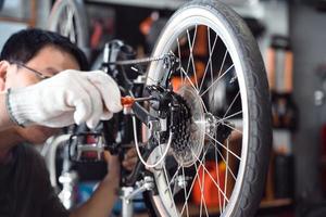 el mecánico de bicicletas ajusta el desviador trasero y repara la bicicleta en el taller. ,concepto de reparación y mantenimiento de bicicletas foto