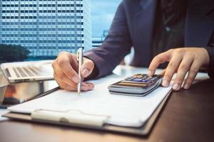 Business man working on desk office ,writing make note and using a calculator at home office. finance accounting concept photo