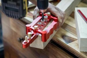 carpenter use drill bit and centering dowel jig tool to make strong joints . woodworking concept.selective focus. photo